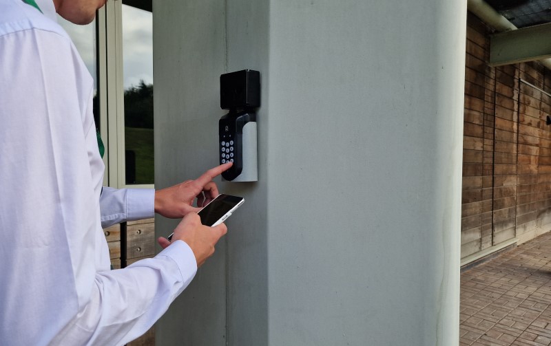 A man opening a SentriGuard key safe with the Access+ app