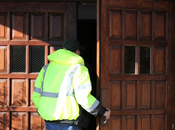 A man wearing a high-vis opening a door